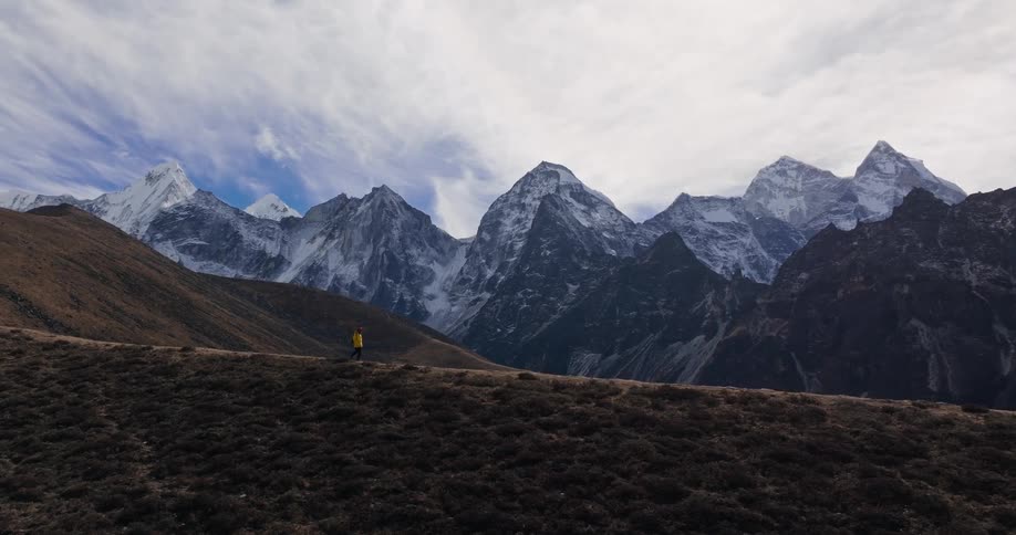 Person hiking on a hill surrounded by snowy mountains