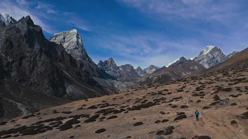 A hiker walks across a flat area near mountains