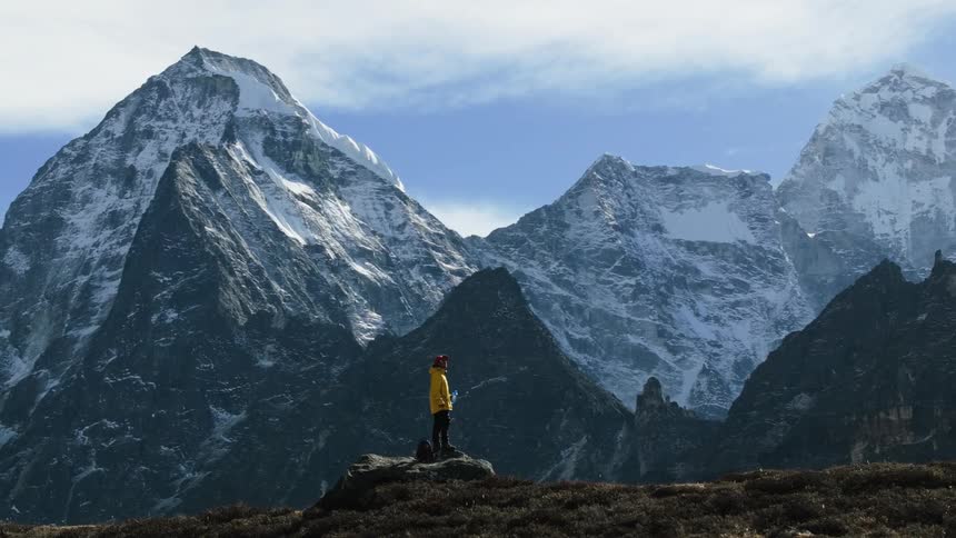 Aerial of a person drinking water on top of a mountain on a cold day
