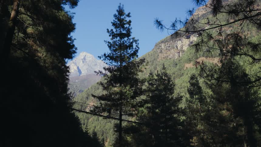 Landscapes of mountains in a forest with a person crossing on a bridge in a natural environment during the day