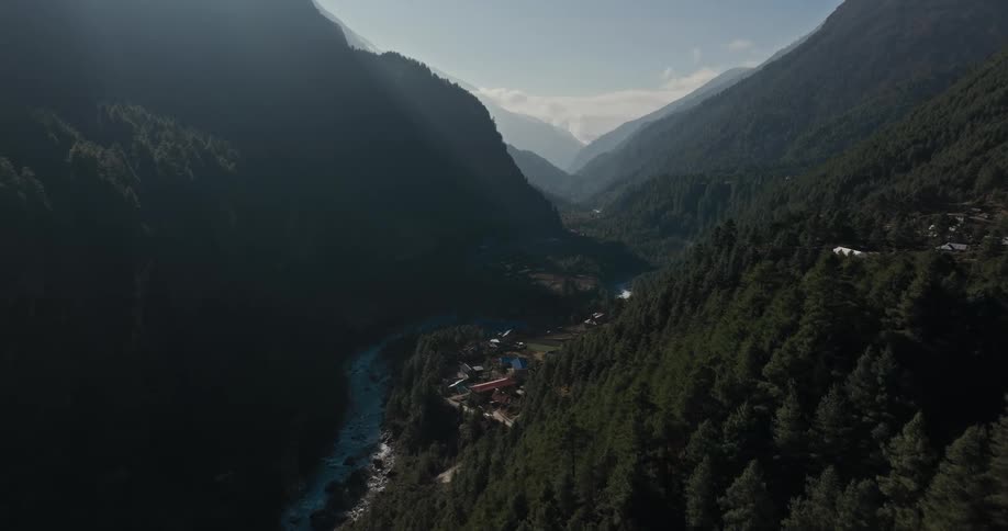 An aerial view of a forestcovered region and a small town next to a river