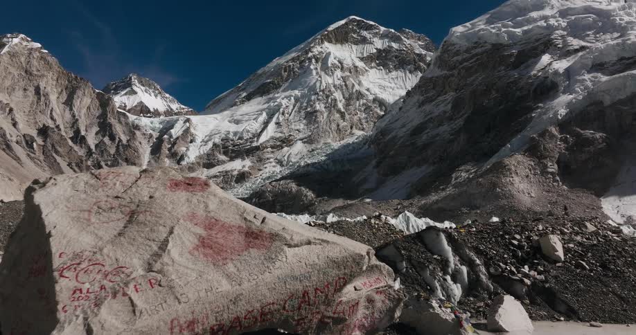A rocky plateau with ice formations at the foot of a snowy mountain range