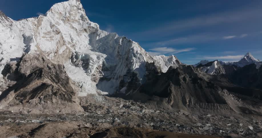 A large mountain of rocks and its top is covered in snow and the sky is blue