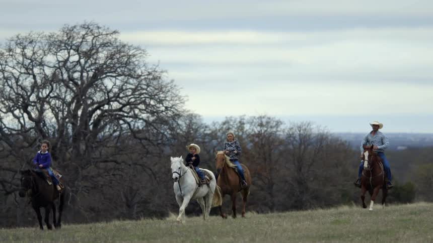 Four people ride horses in a field