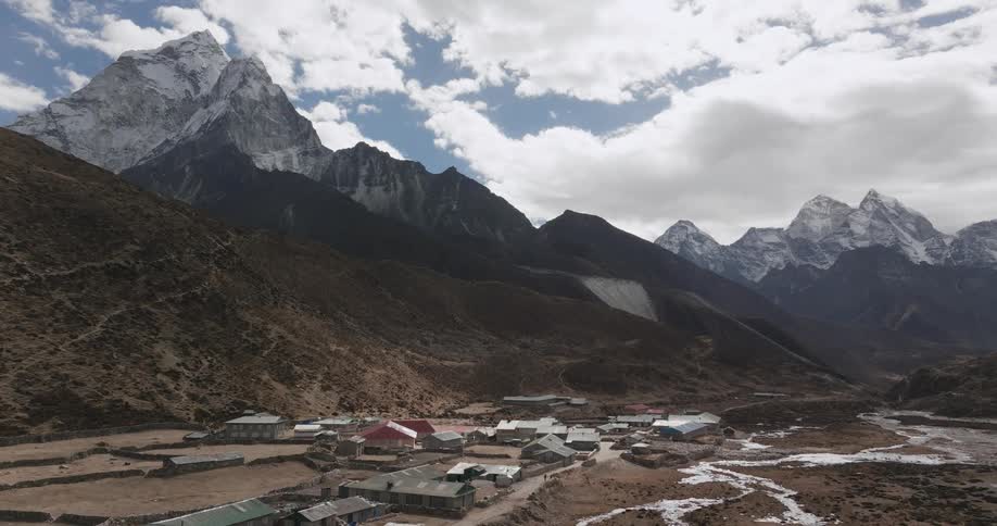 Community on a natural land surrounded by snowcapped mountains on a blue sky day with clouds