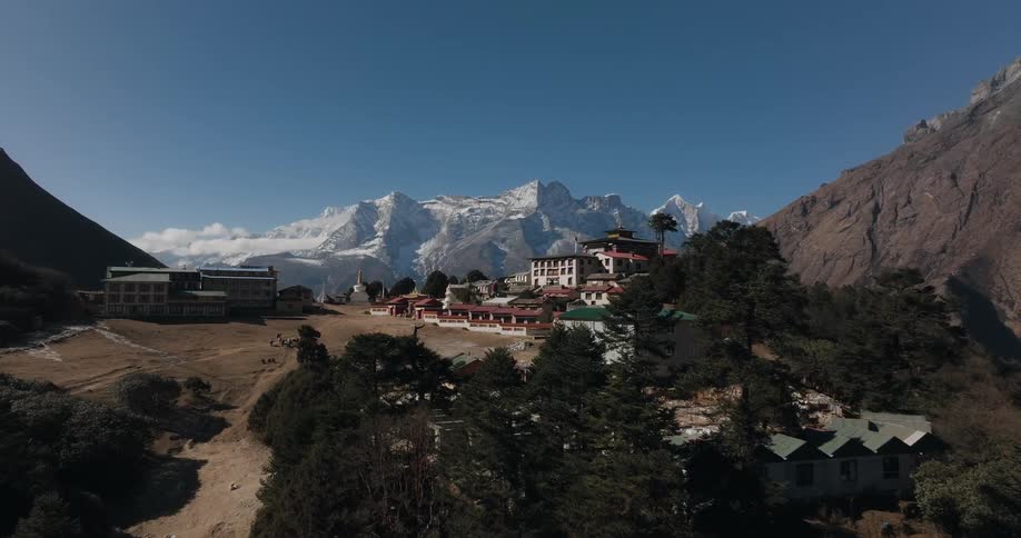 A village with many houses in a rural region on top of the mountains and behind there is a huge mountain with snow on top