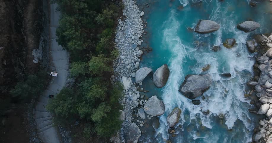 A person walking down the steps of a trail following a river with rapids