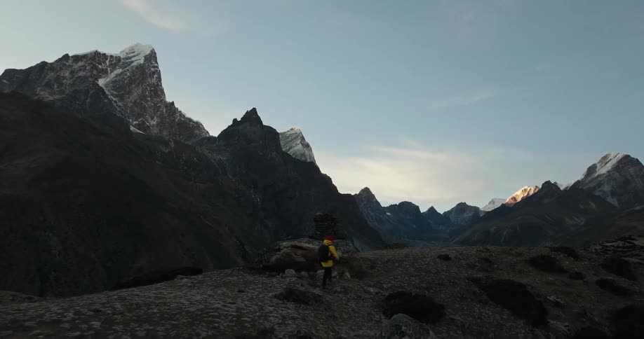 Back of a man walking on mountain with a backpack during the day