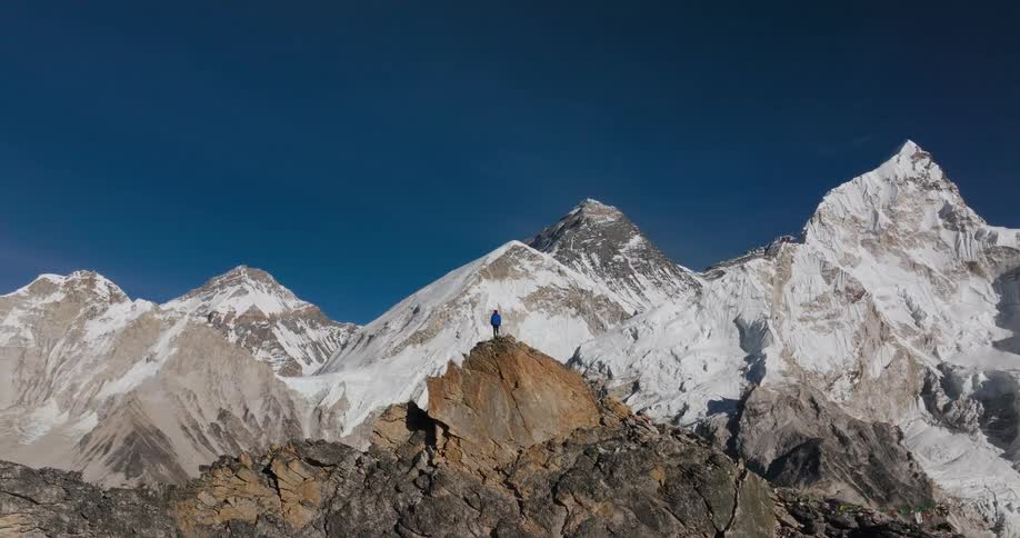 A person standing at the peak of a mountain during the day