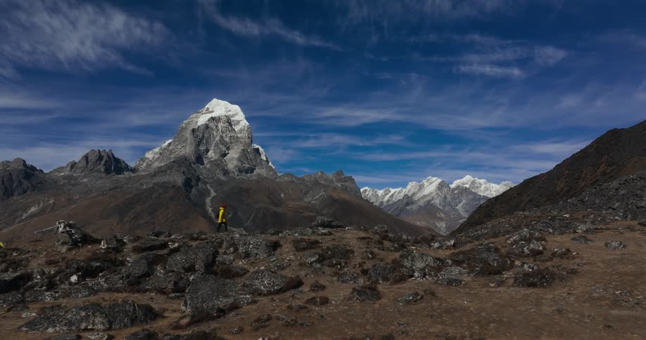 Man hiking on barren ground with rocks and mountains around