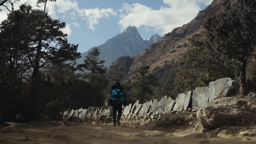 A hiker walking along a path in the direction of a mountain range
