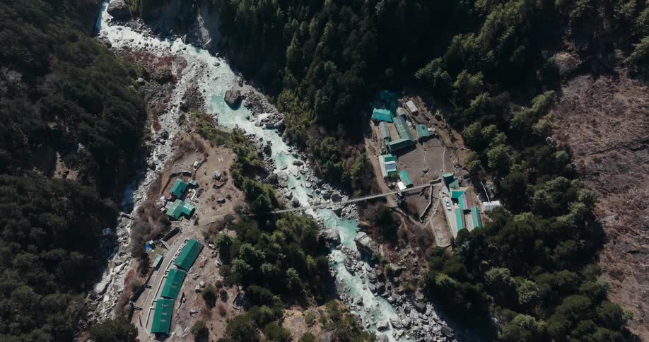 Aerial of a small village hidden in the mountains between a small river