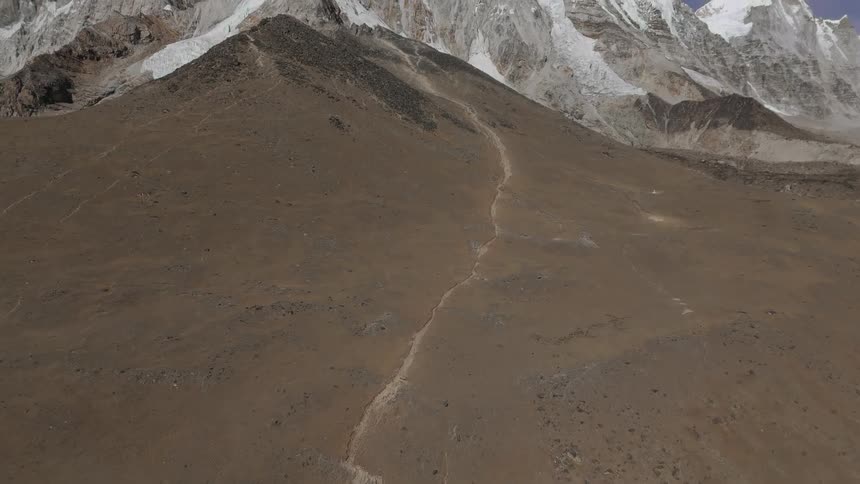 A path extends across a flat area and then up a mountain slope