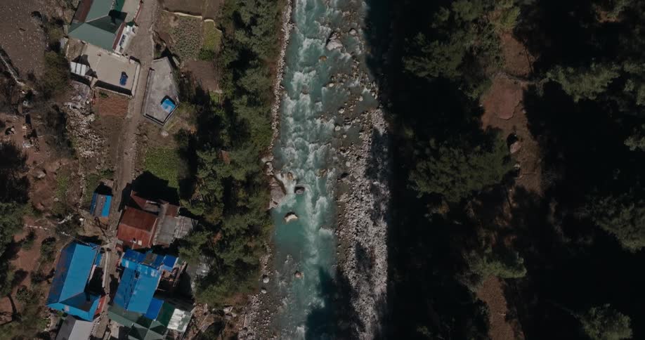 Aerial of a village on the banks of a river in the mountains