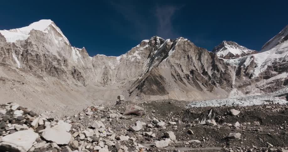 Ground with stones and rocks and surrounding mountains with cliffs and snow