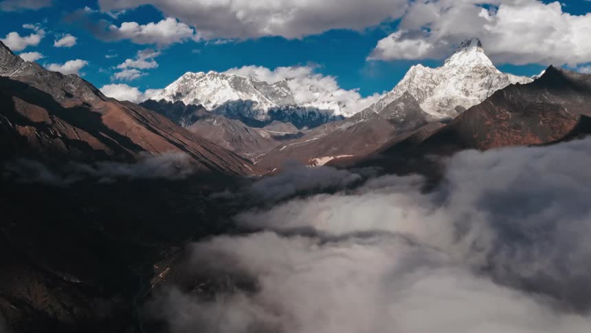 Landscape of clouds passing through the mountains with their peaks covered in snow