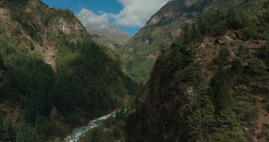Aerial of a village hidden between mountains and forests