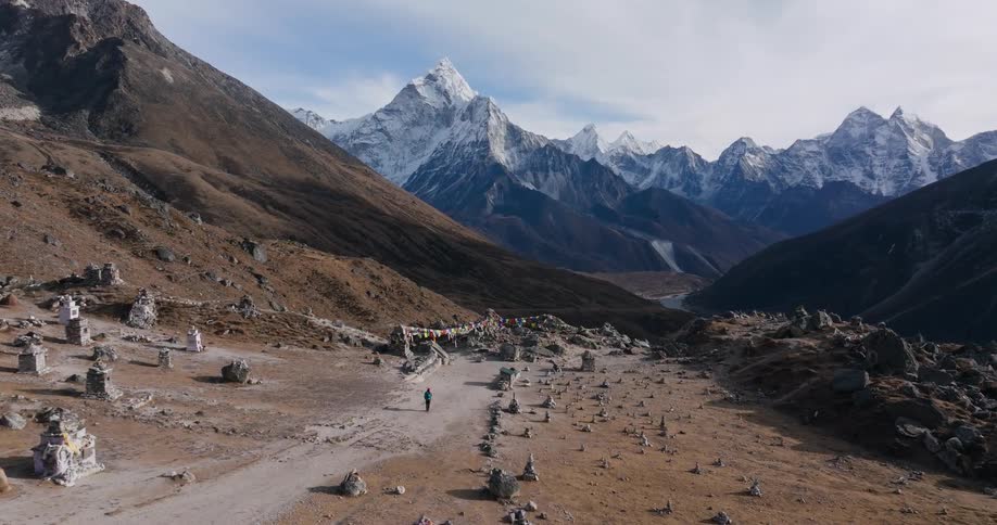 A person walking on a path where in front there is a landscape of several mountains