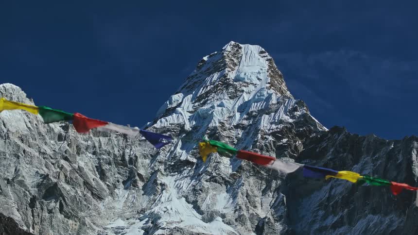 Flags flutter in the wind near a large mountain