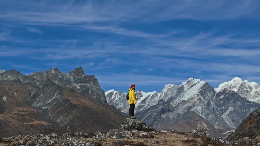A man standing at mountain top at midday while looking around