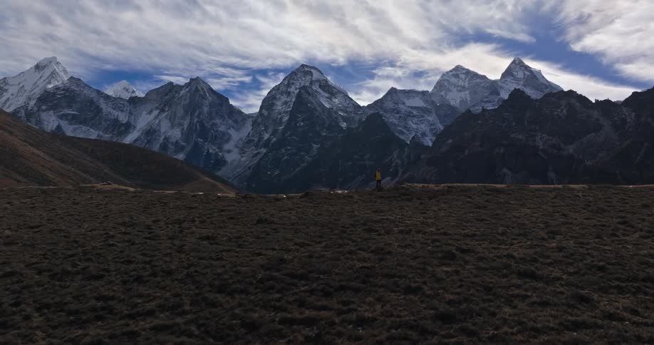 A man is shown walking across from a mountain range in a valley