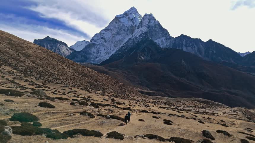 Two people hiking on desert ground surrounded by mountains on a winter day