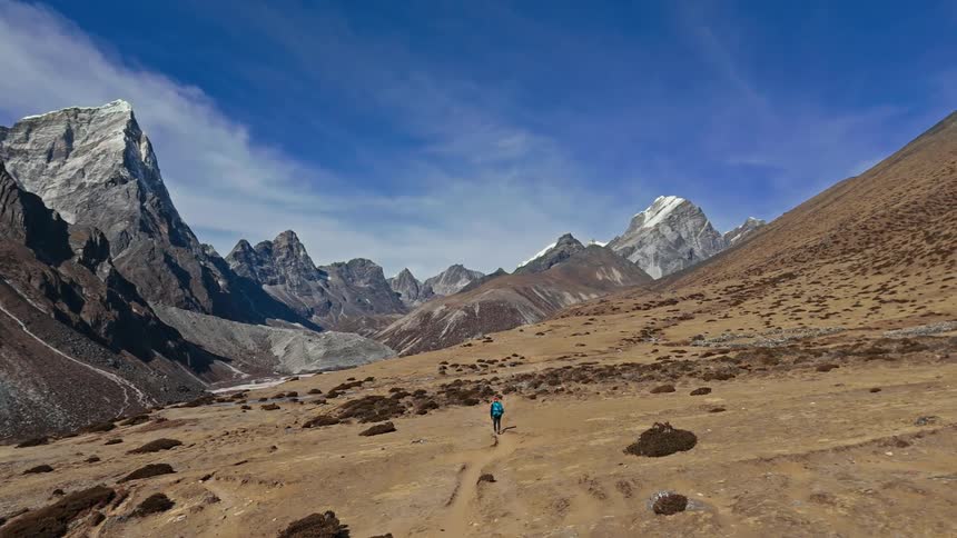 A person walking alone through the mountain valley during the day