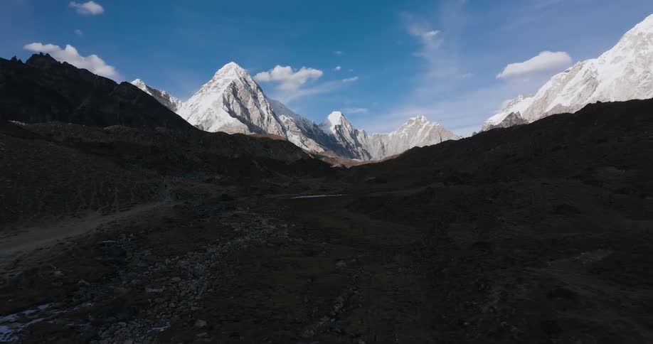 A path across a rocky plateau leading to a snowy mountain range