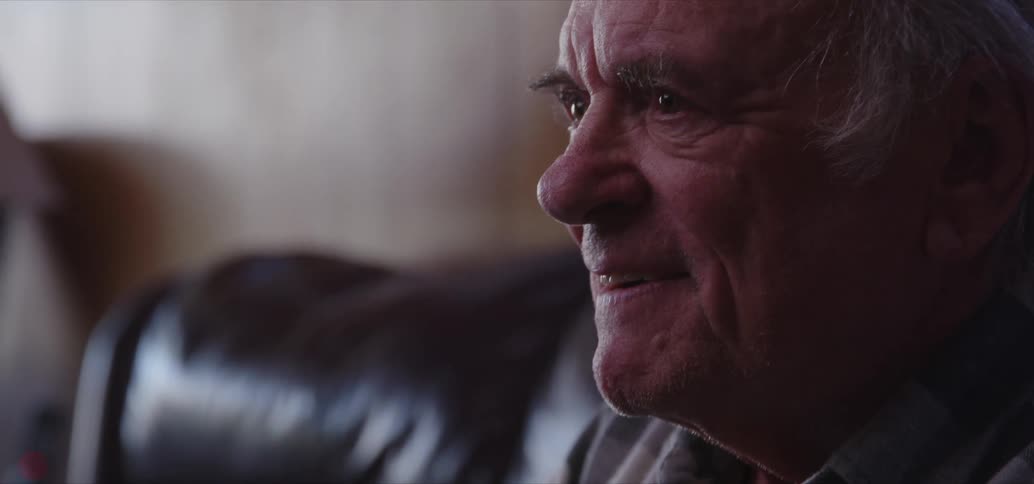 Elderly man sitting inside a sofa concentrated playing video games