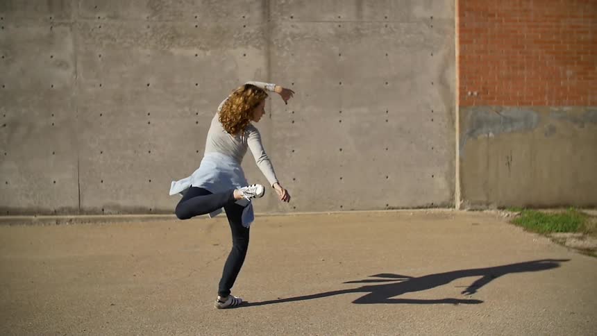 Woman spinning around and doing ballerina dance move outside