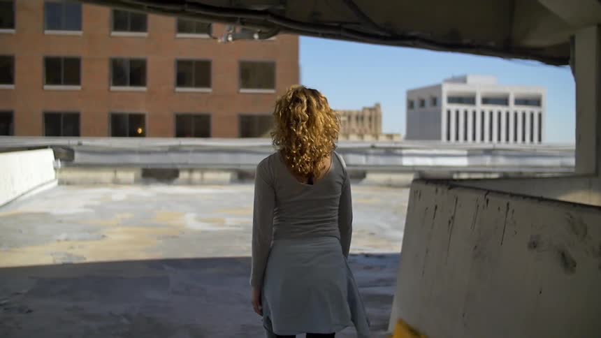 A woman walking in a parking lot area that is secluded