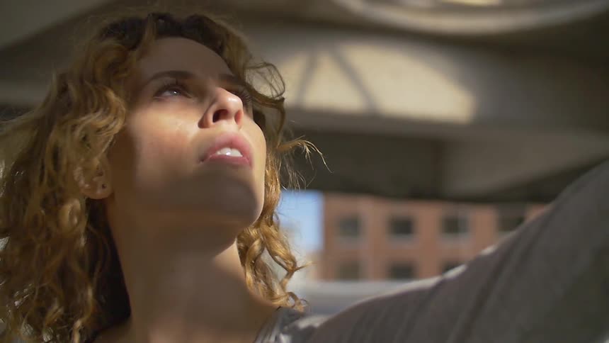 A woman is reaching up looking towards the sky