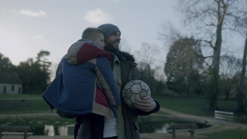 A father holds his son and a soccer ball