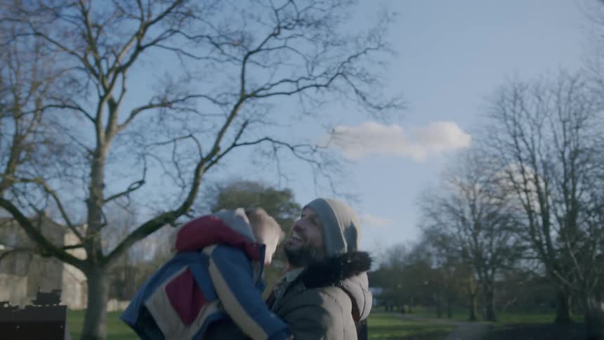 A father tosses his son up and down in the playground