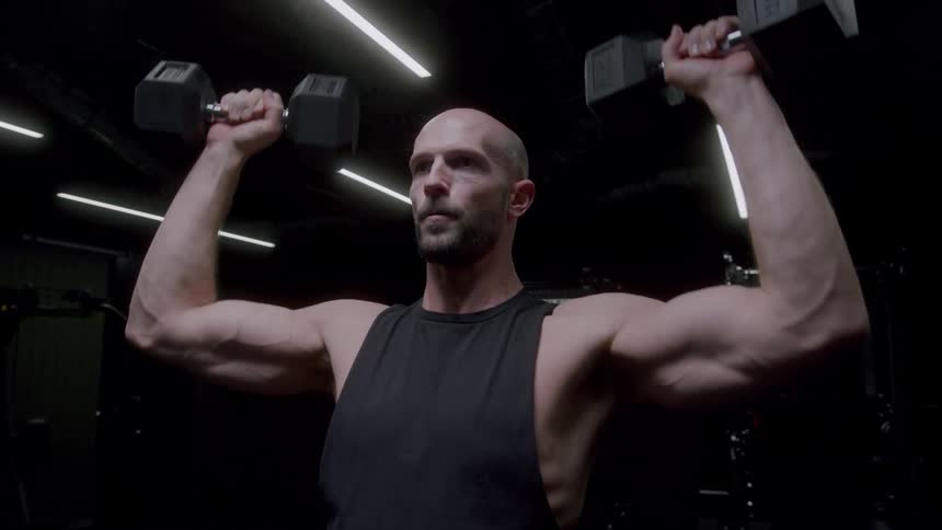 A man lifting weights in a dark gym