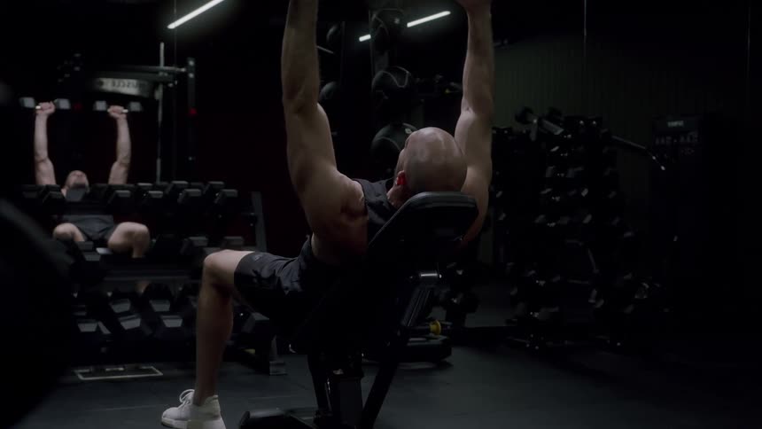 A man is lifting dumbbells in the gym