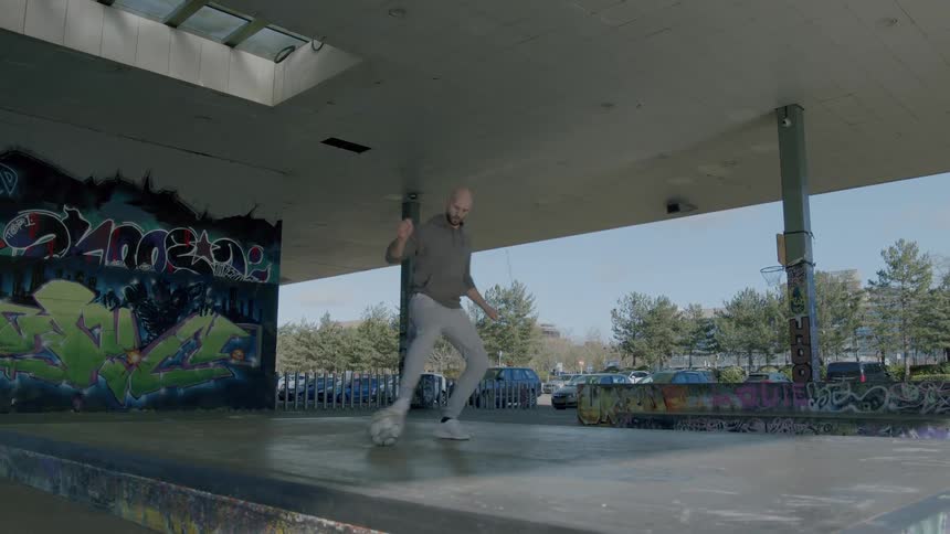 A man in a concrete terrace playing with a soccer ball