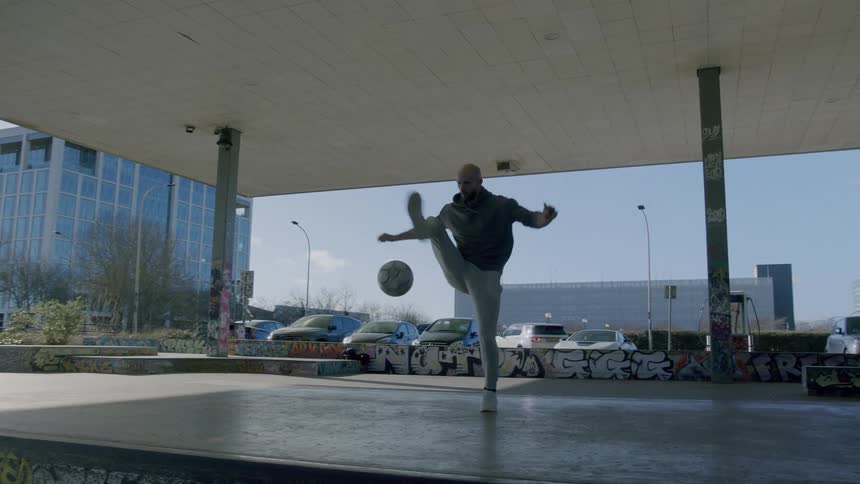 Man doing freestyle with a soccer ball in an open lobby