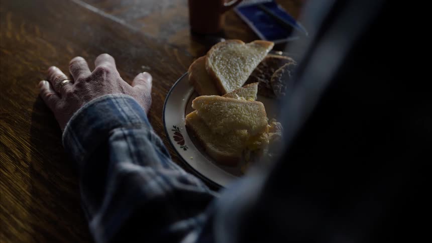 Hands of an elderly person with a fork eating omelet with slices of bread