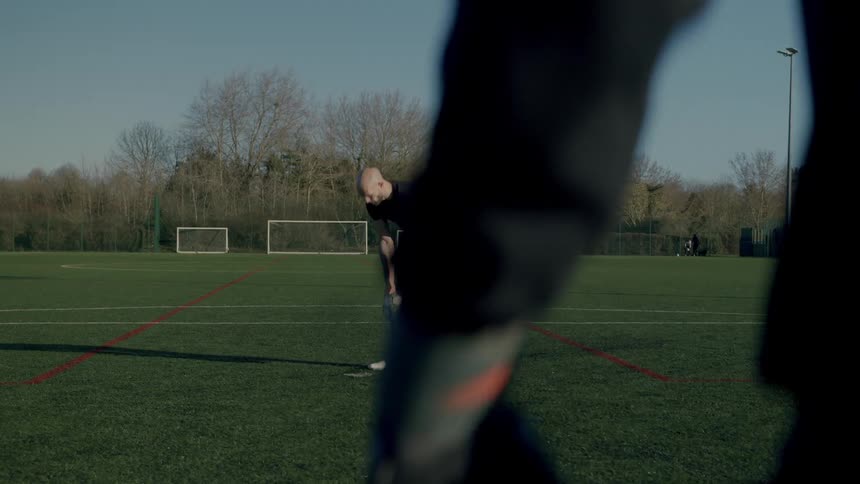 A man places the soccer ball on the ground