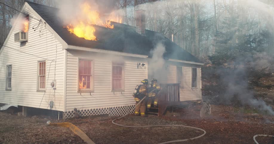 Firefighters try to put out a fire in a house in a suburban neighborhood