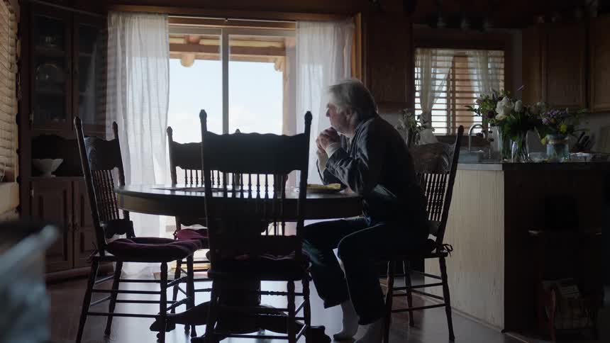 Elderly man sitting at a table during the day while having lunch