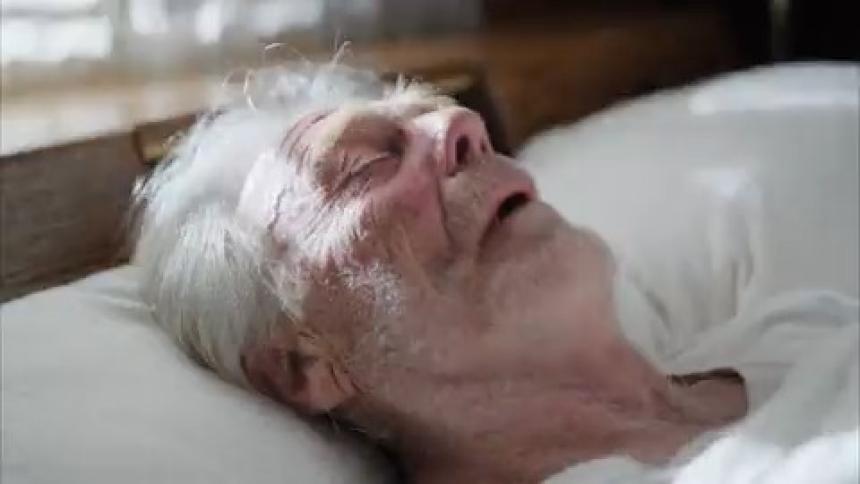 Portrait of an elderly man sleeping when outside lights pass by and he wakes up scared