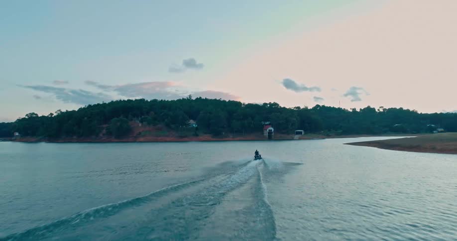 A person rides a jet ski near a coast