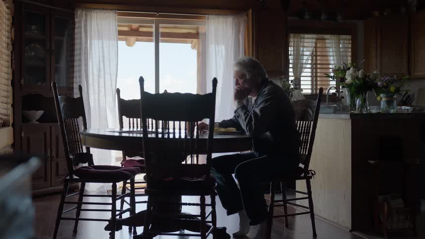 Elderly man sit at the dining table thinking with his hands on the chin at midday