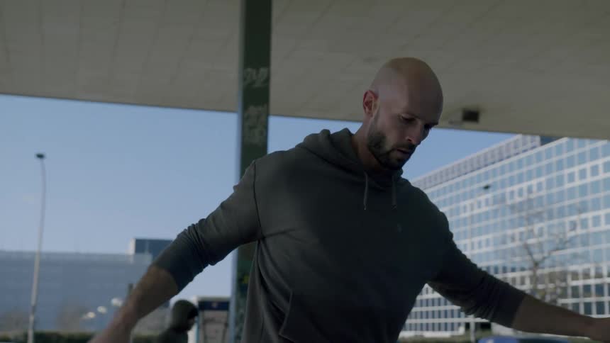 A man playing football in a city park during the day
