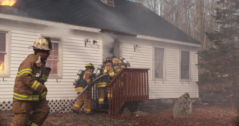 Firefighters rush into a burning home