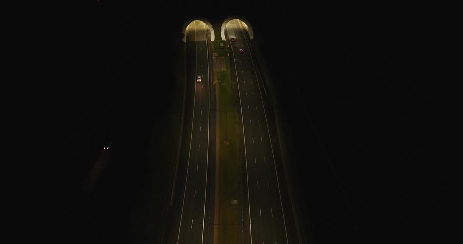 An aerial view of cars driving into a tunnel in a city