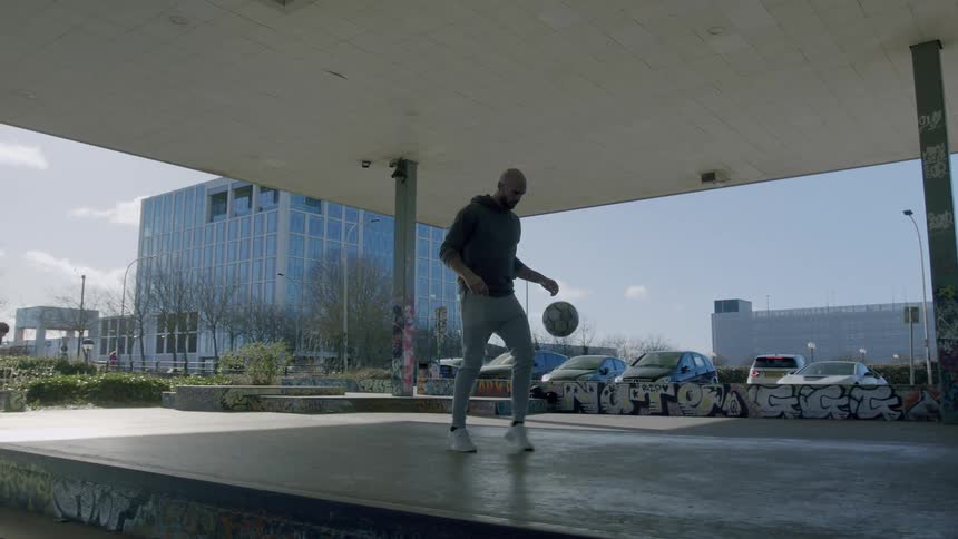 Man in an open lobby performing tackles with a soccer ball