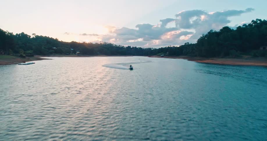 Aerial of a person riding a jet ski on an island during sunset